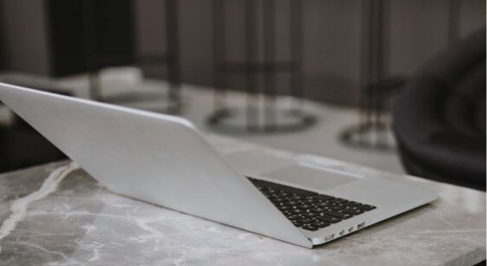 Imagem de um notebook apoiado em uma mesa de mármore.